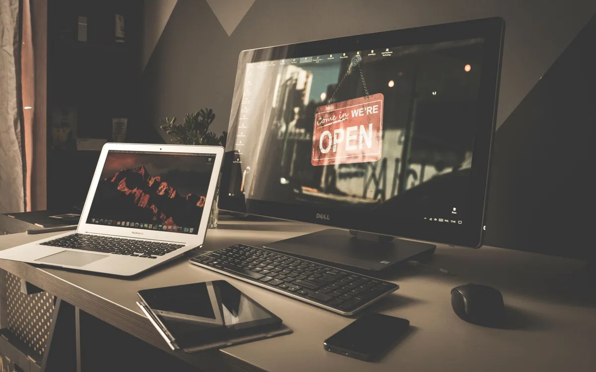 A home workspace with a monitor, laptop, keyboard, and digital devices.