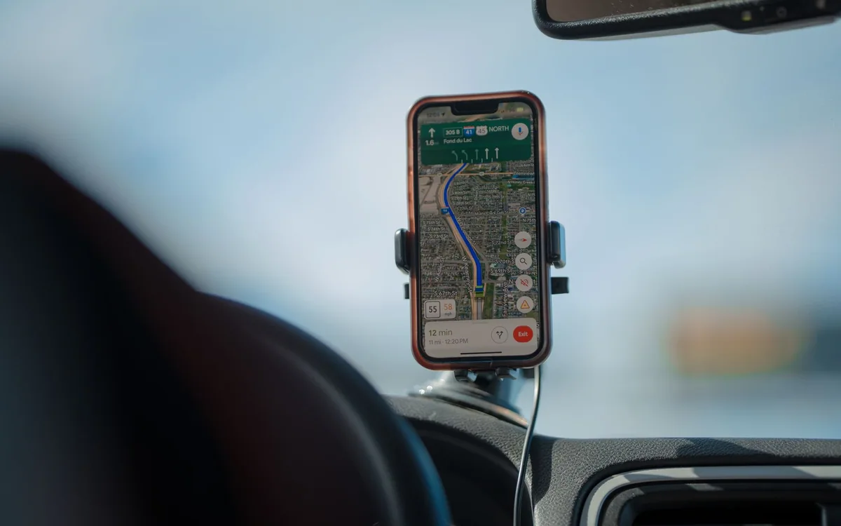 A smartphone displaying navigation is mounted on a car dashboard.