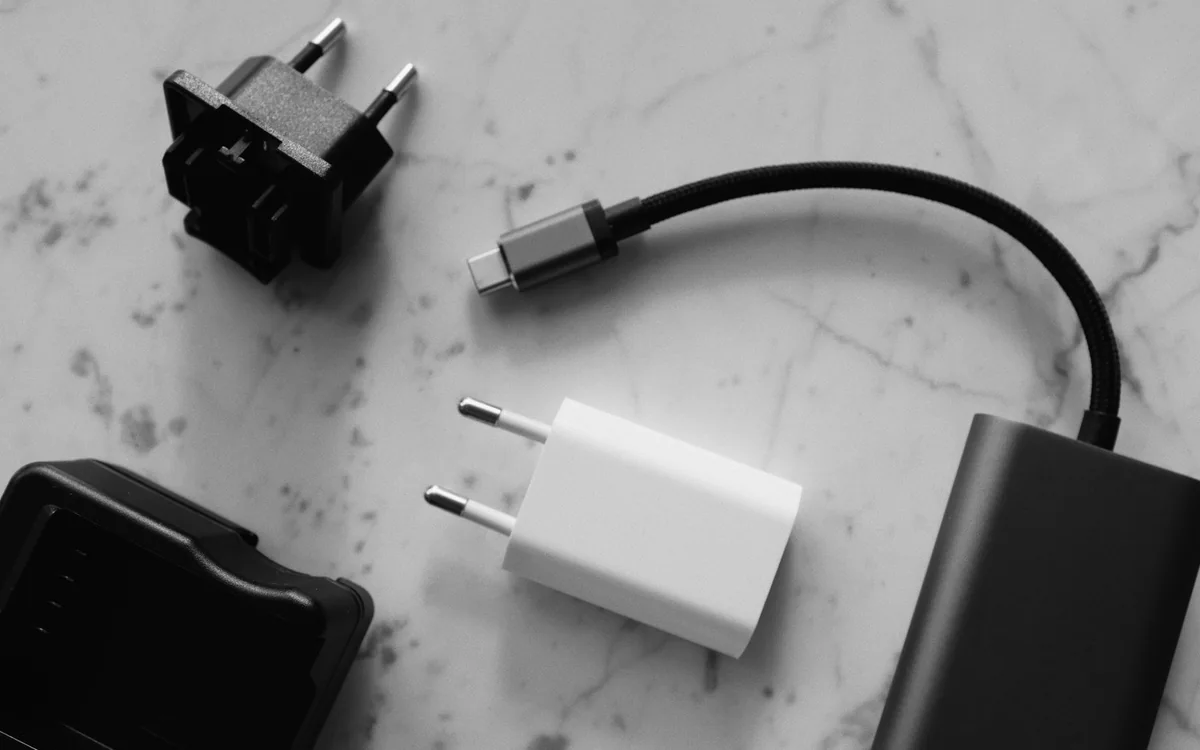 Charging adapters, a portable battery, and cables arranged on a marble table.