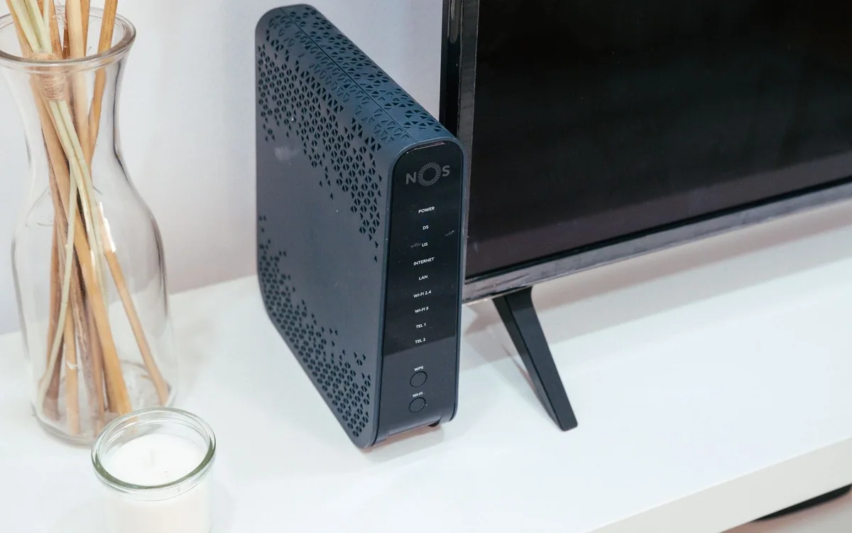A wireless router sits beside a television and decorative items in a home.